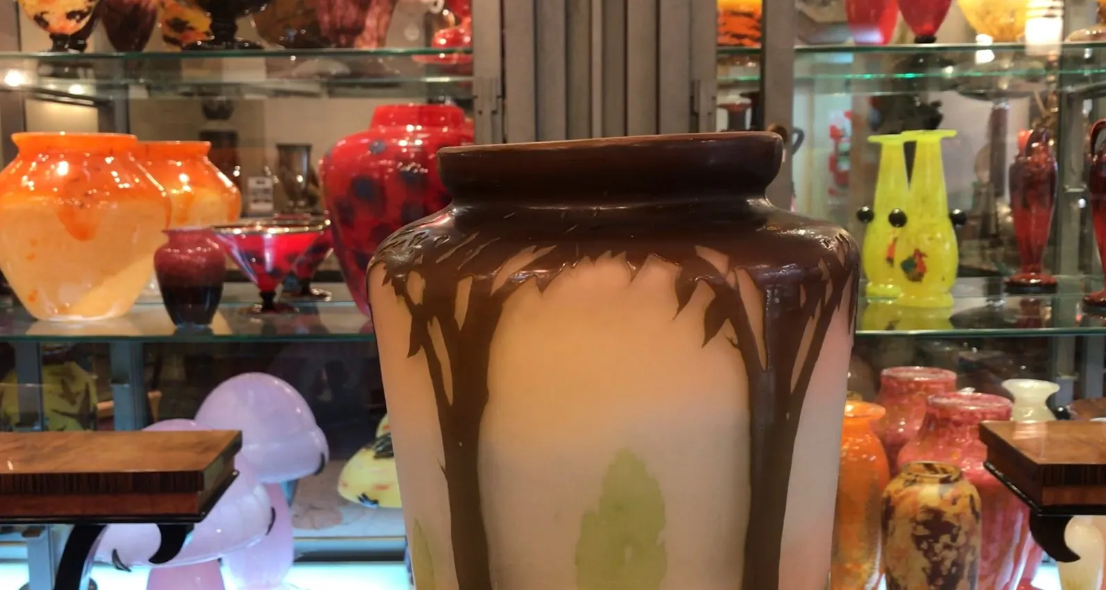 古老的签名玻璃瓶Gallé，棕色和绿色装饰，浅色背景。周围有其他装饰物品。