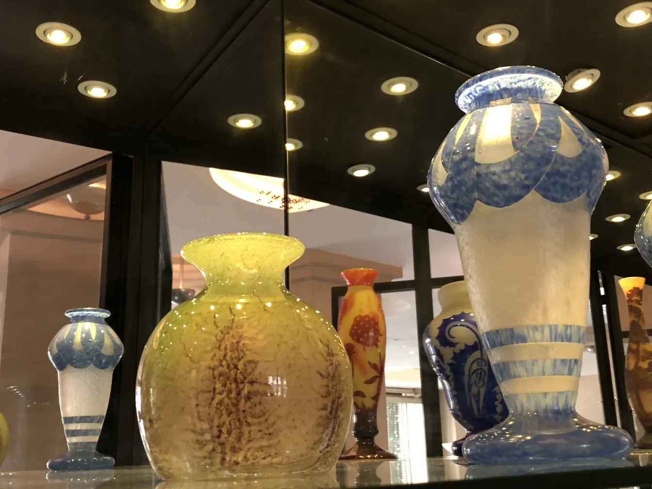 Vases of signed glass in display case, various colors