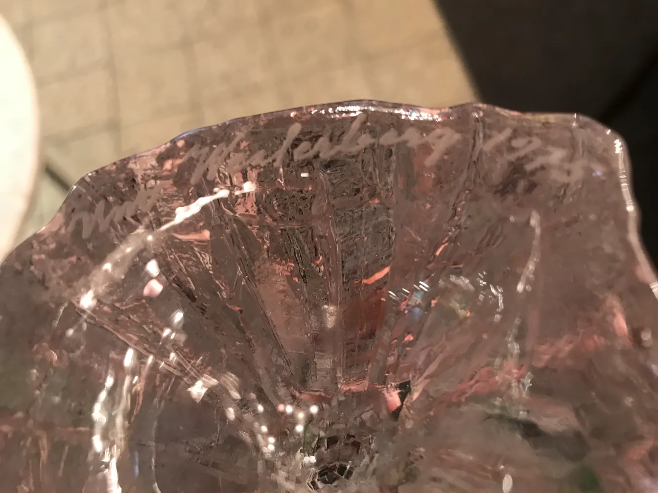 Vidrio firmado antiguo con detalles decorativos en tonos variados.