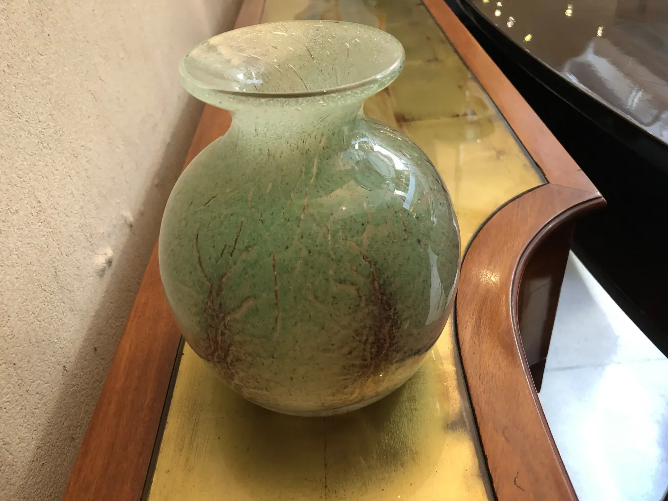 Signed glass vase featuring a natural branch-like design in green tones.