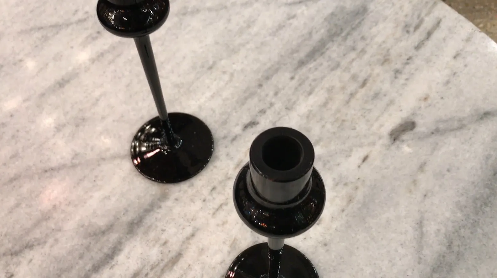 two black candle holders on a light marble table