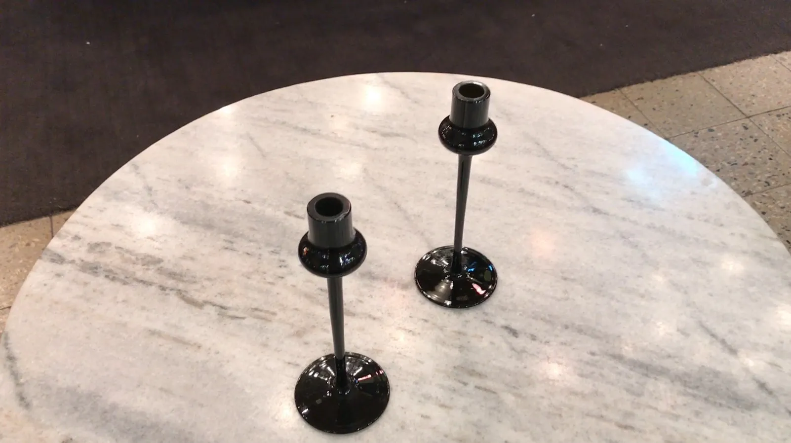 duas velas de vidro assinado sobre mesa de mármore