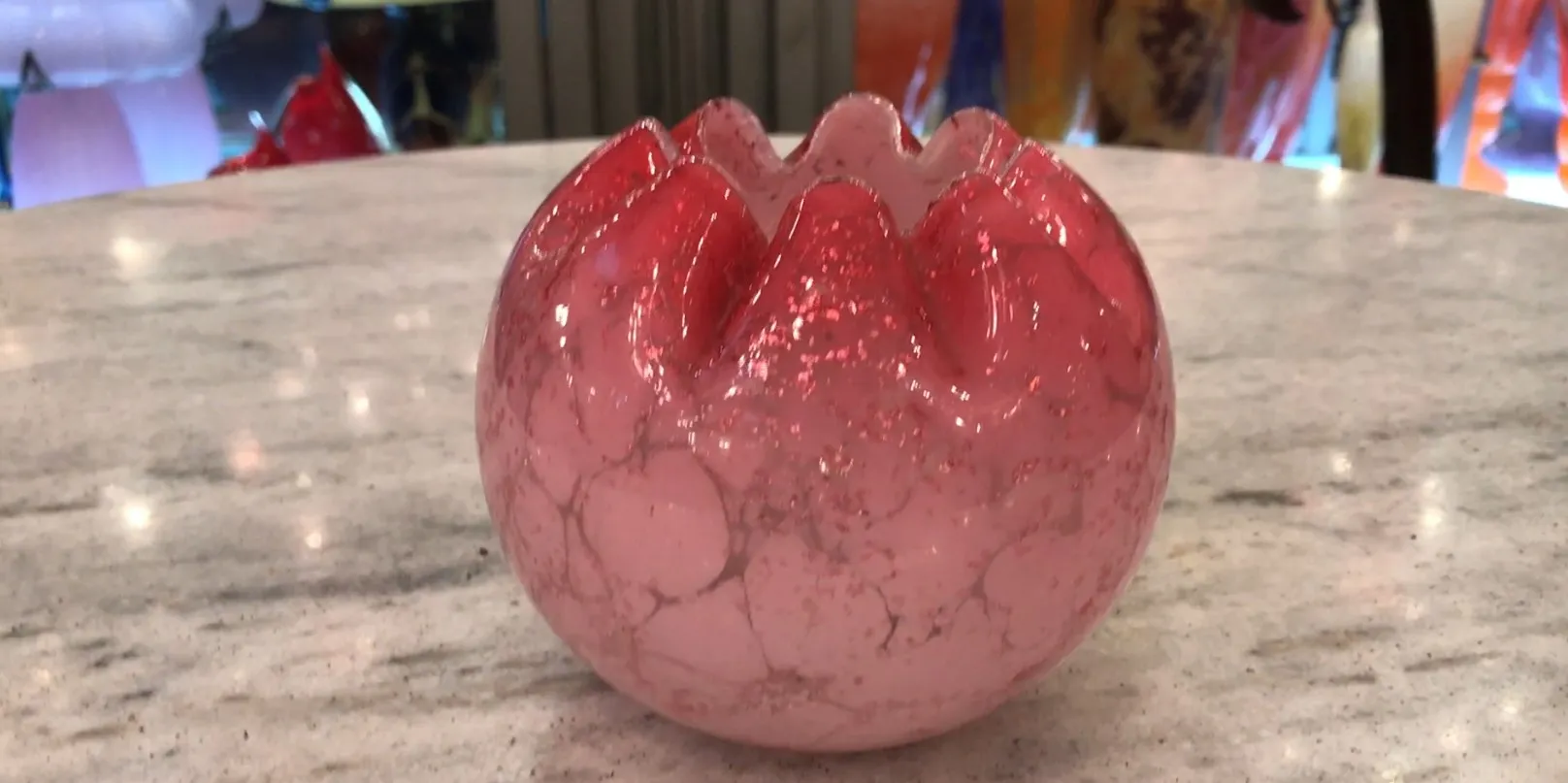 Vetro con firma in tonalità di rosso, decorazione antica su tavolo di marmo.