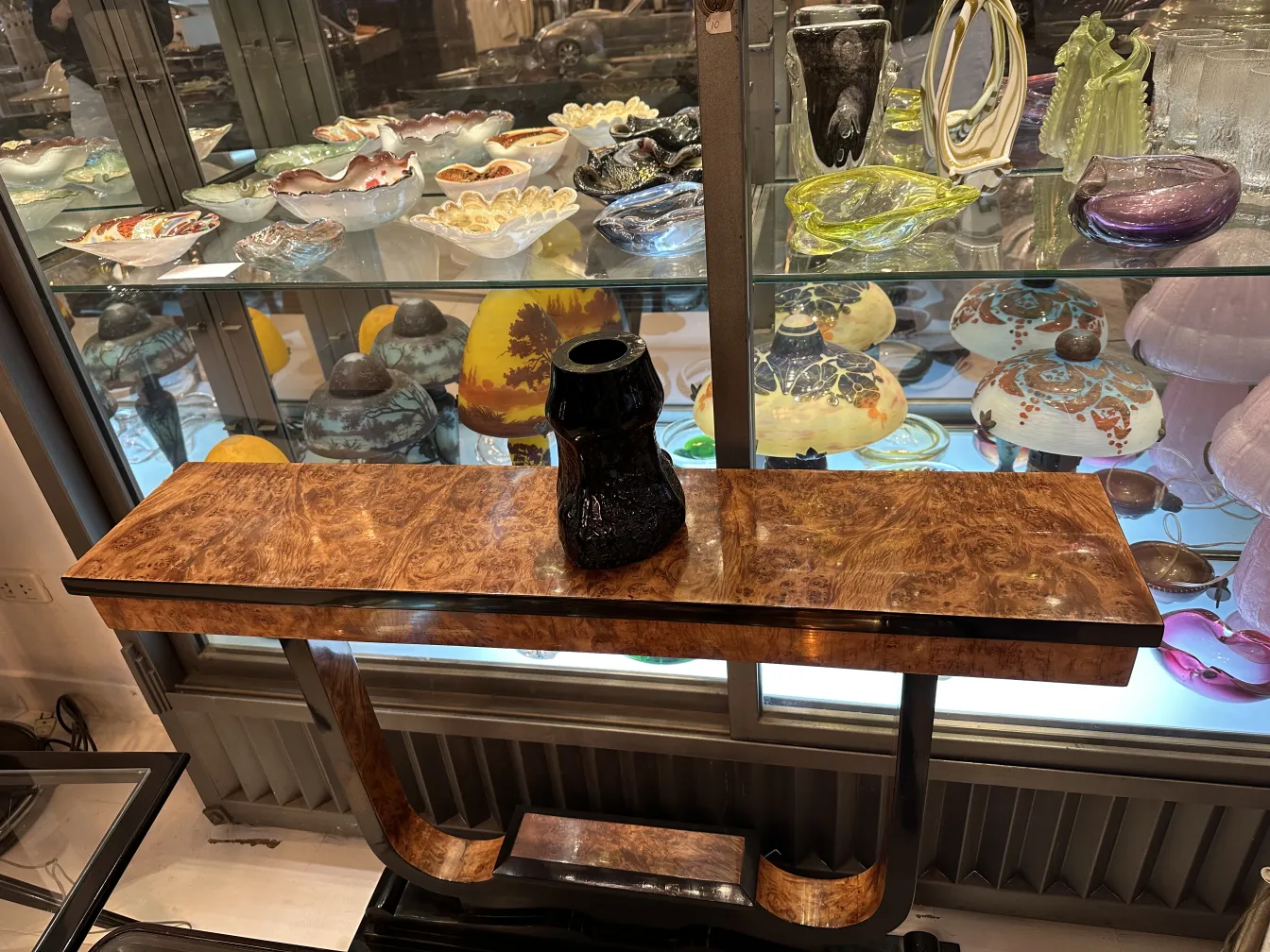 Antikes signiertes Glas, das zwischen verschiedenen Antiquitäten ausgestellt ist. Stilvoller Tisch.