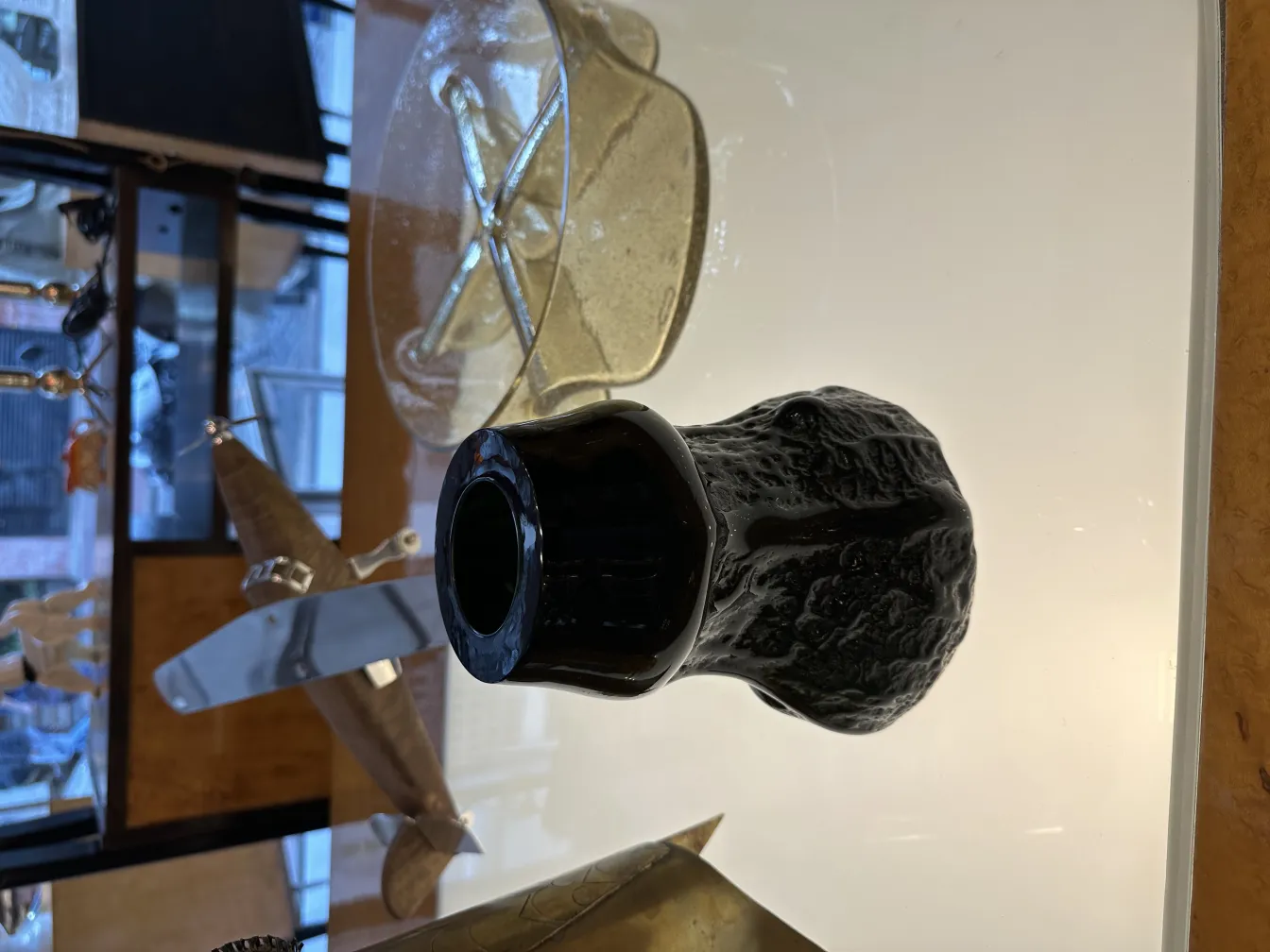 Verre signé avec surface complexe et forme élégante, entouré d'antiquités.