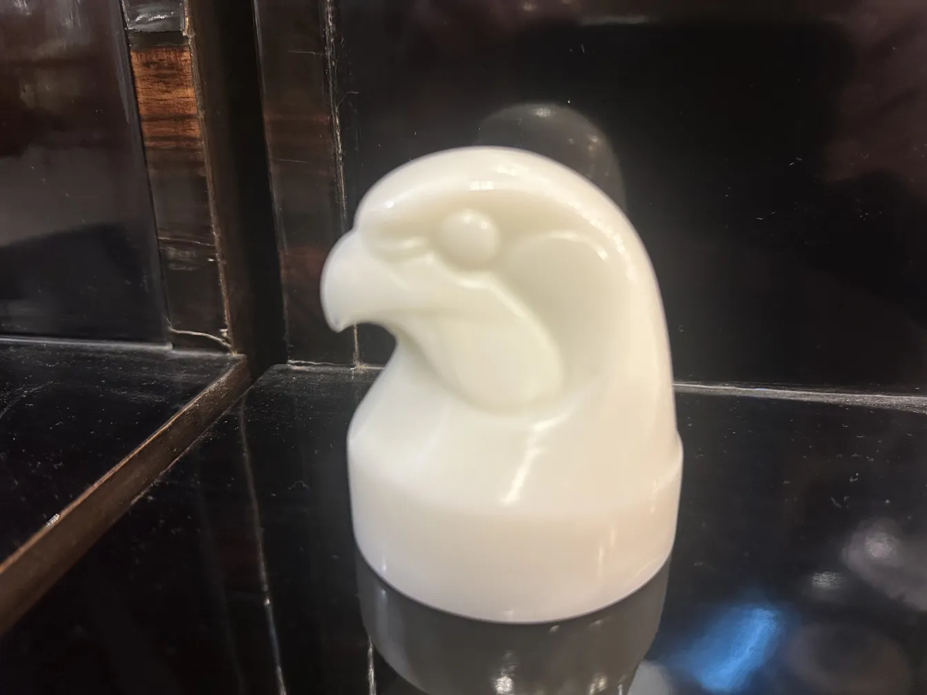 Busto antiguo de pájaro en vidrio firmado, fondo oscuro.