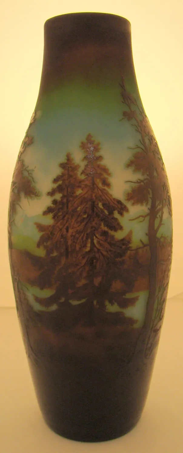 Vaso de vidro antigo com paisagens e árvores gravadas.