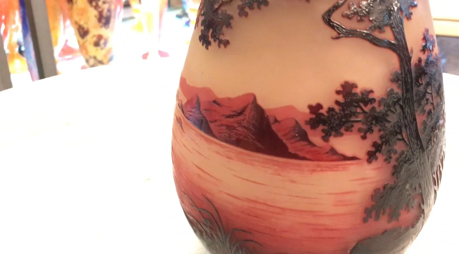 Garrafa de vidro antiga assinada D'Argental, com uma paisagem de montanhas e árvores.