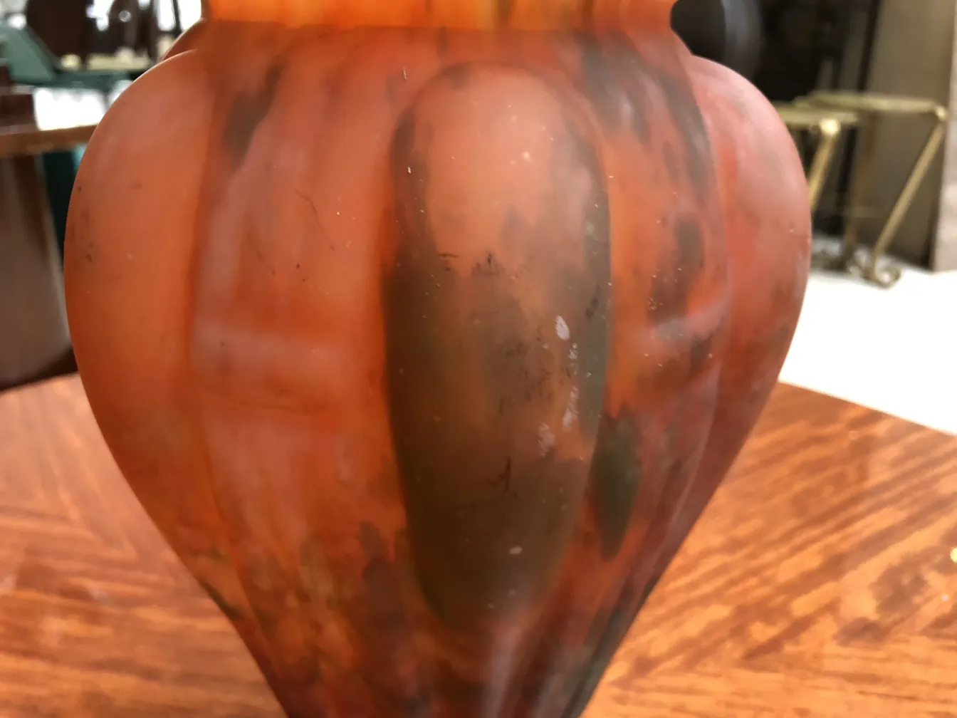 Antique signed Lorrain glass vase with warm colors in a cozy setting.