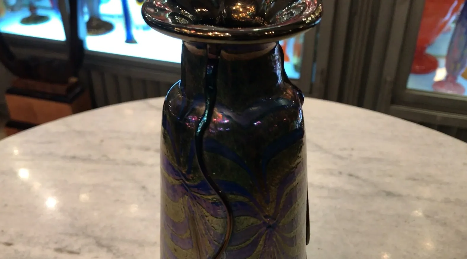 Antique signed glass Loetz with decorative blue and gold design, displayed on a marble table.