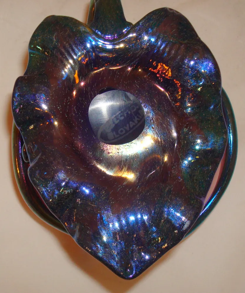 Verre décoratif signé Loetz avec un design coloré et brillant dans un environnement vintage.