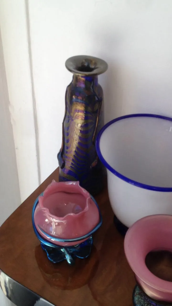 Vidrio antiguo firmado de Loetz en colores vivos, decorado con un diseño distintivo, acompañado de otros objetos decorativos.