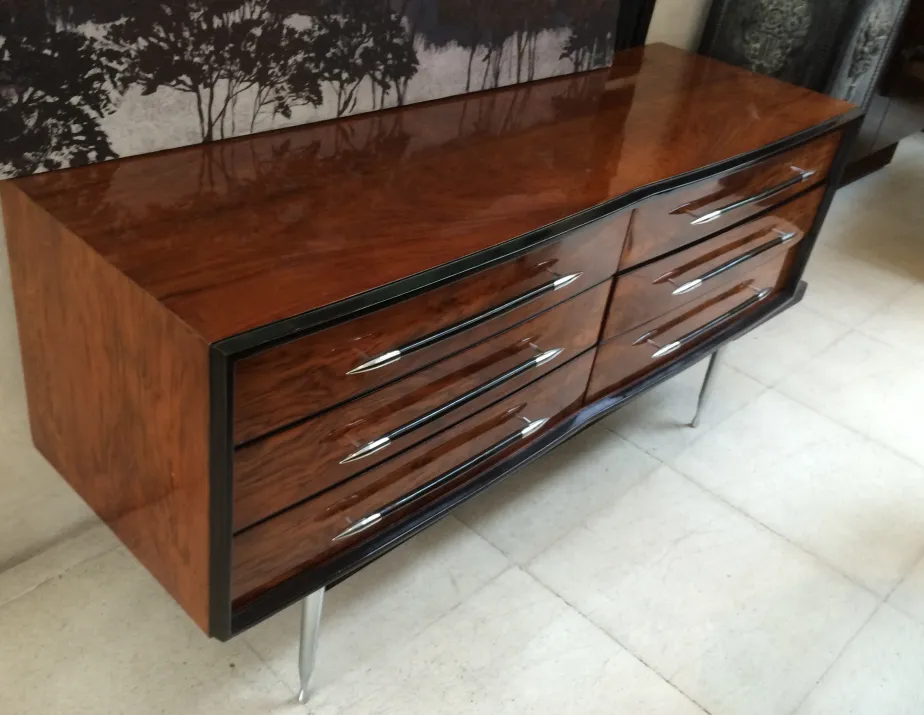 criado-mudo antigo com acabamento brilhante e quatro gavetas elegantes em um ambiente aconchegante.