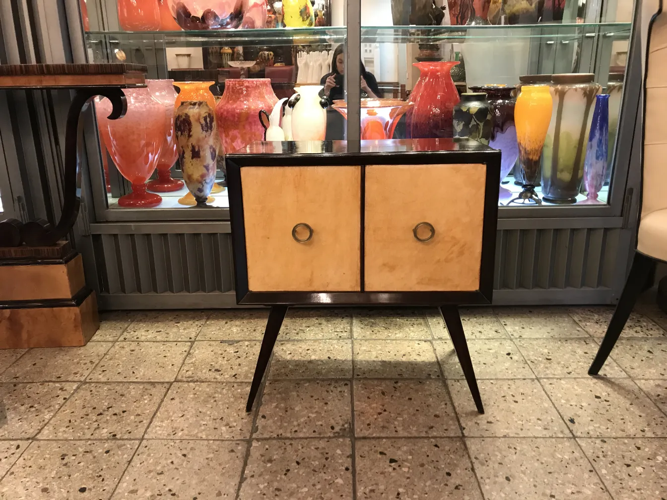 table de chevet antique avec deux portes et anneaux dorés, entourée de divers vases anciens