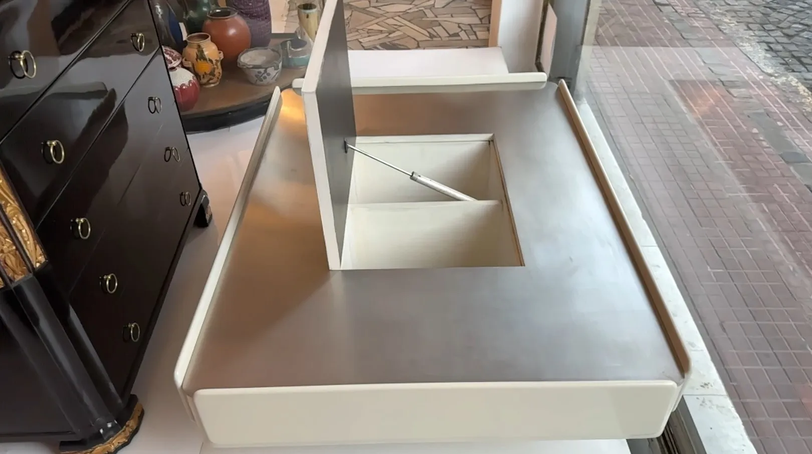 mesa de centro antiga vico magistretti em um ambiente iluminado com objetos decorativos