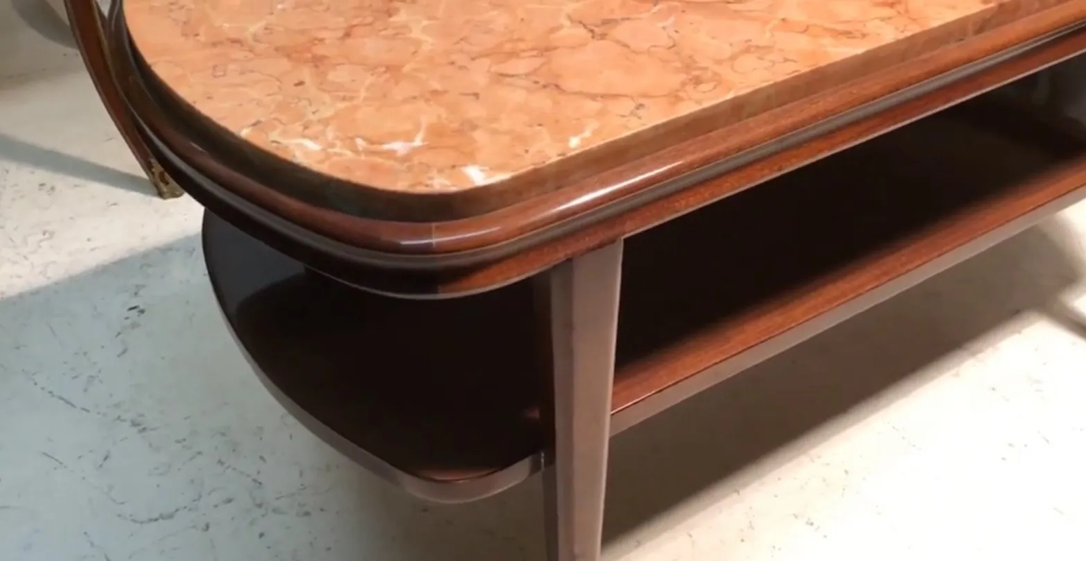 Table basse ancienne avec dessus en marbre et étagère inférieure dans un cadre chaleureux.