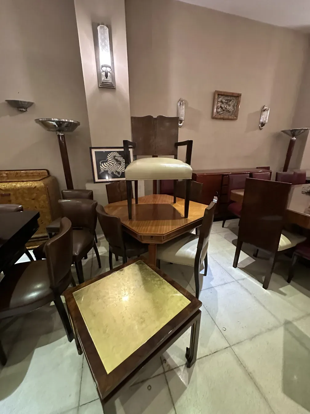 antique coffee table with a gold top, surrounded by chairs