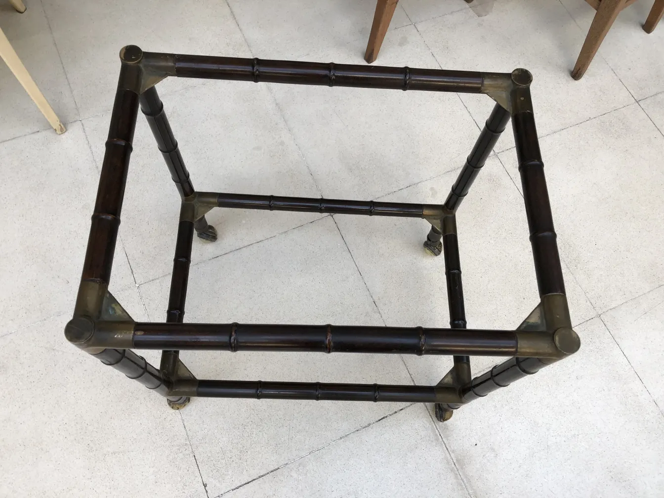 Tavolino antico con angoli arrotondati, circondato da altri mobili.