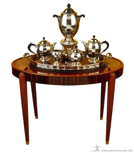 Runder antiker Tisch mit silbernem Teeservice oben.