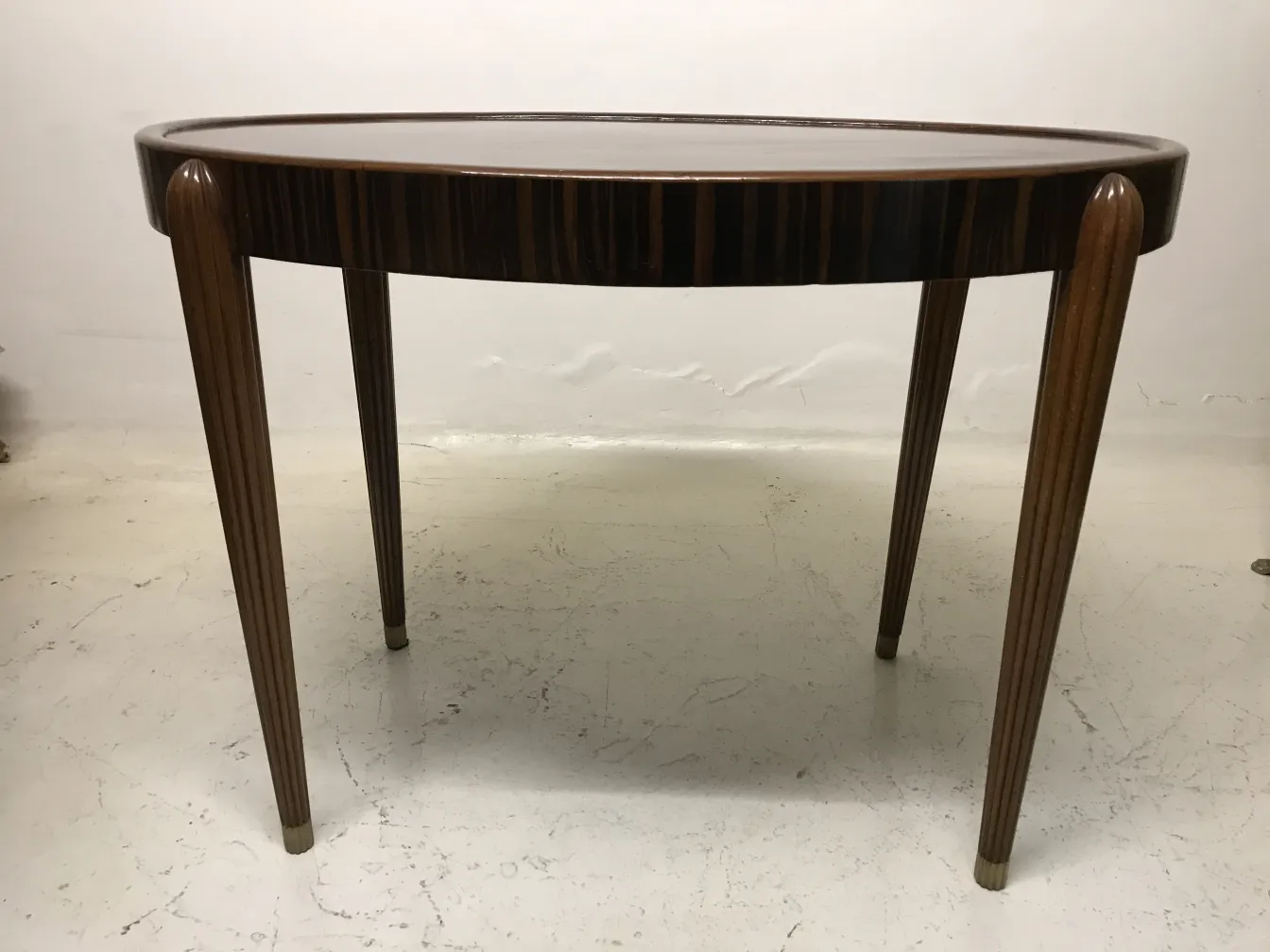 Antique round small table with elegant legs in a minimalistic setting.