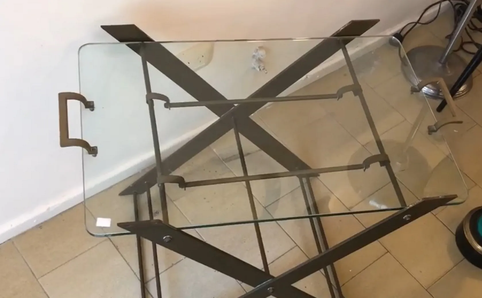 古董小桌子，透明玻璃顶部和交叉金属底座，放在现代环境中