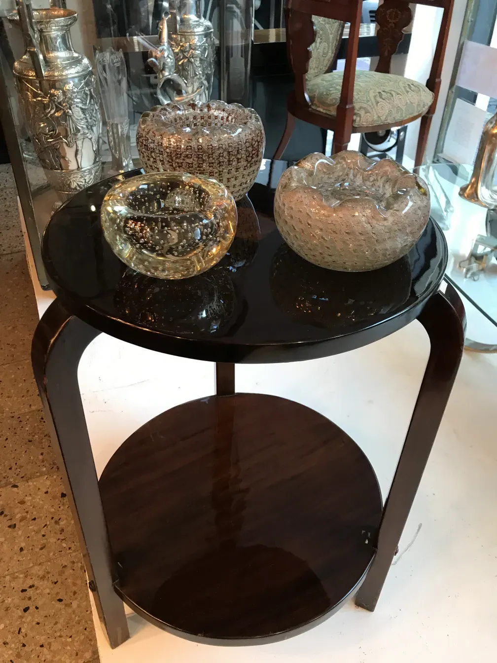 Petite table ronde ancienne avec des bols en verre décoratifs.