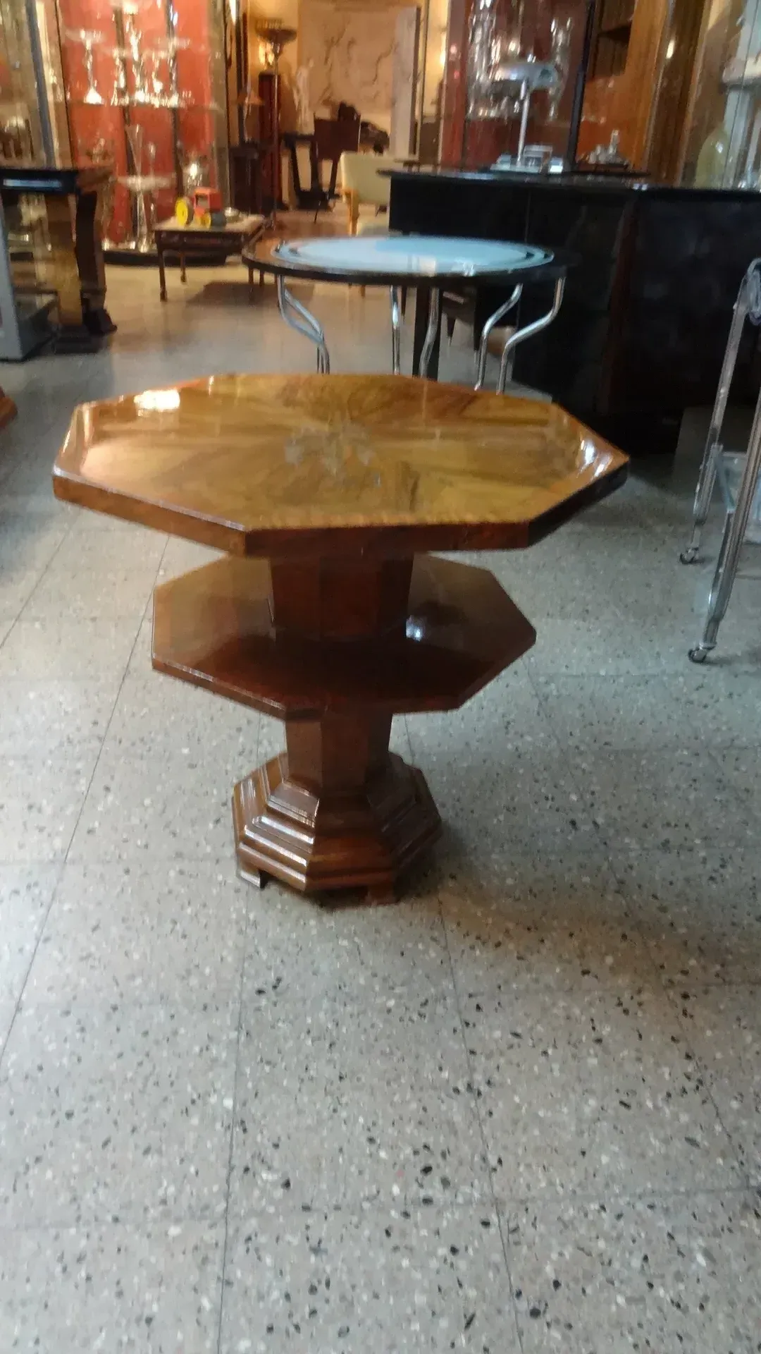 Mesinha antiga de forma octogonal com detalhes decorativos em um ambiente de antiguidade.