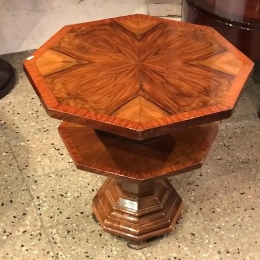 Antique octagonal small table with beautiful top design, surrounded by a classic ambiance.