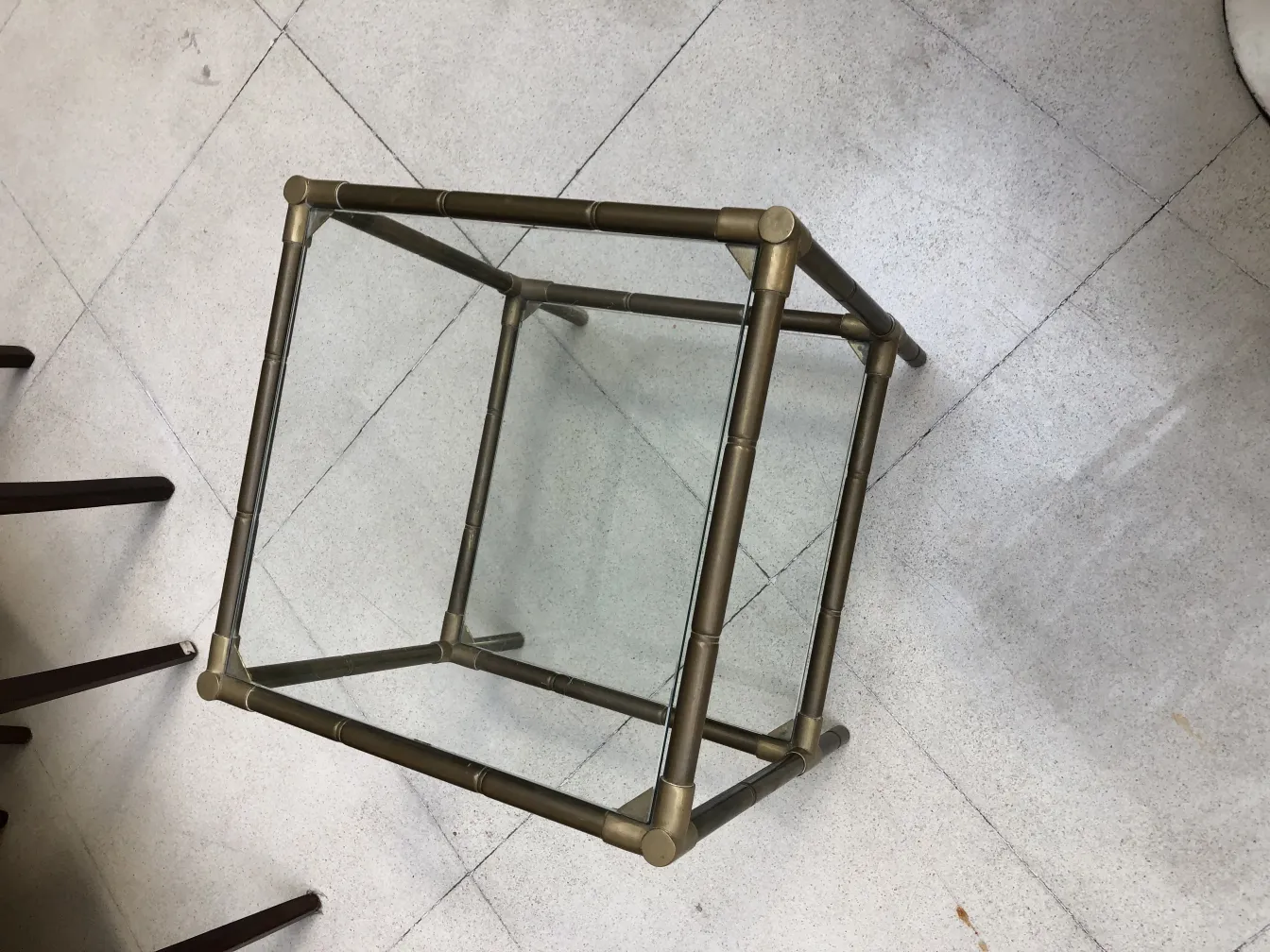 petite table antique avec structure en métal et verre, dans un cadre simple