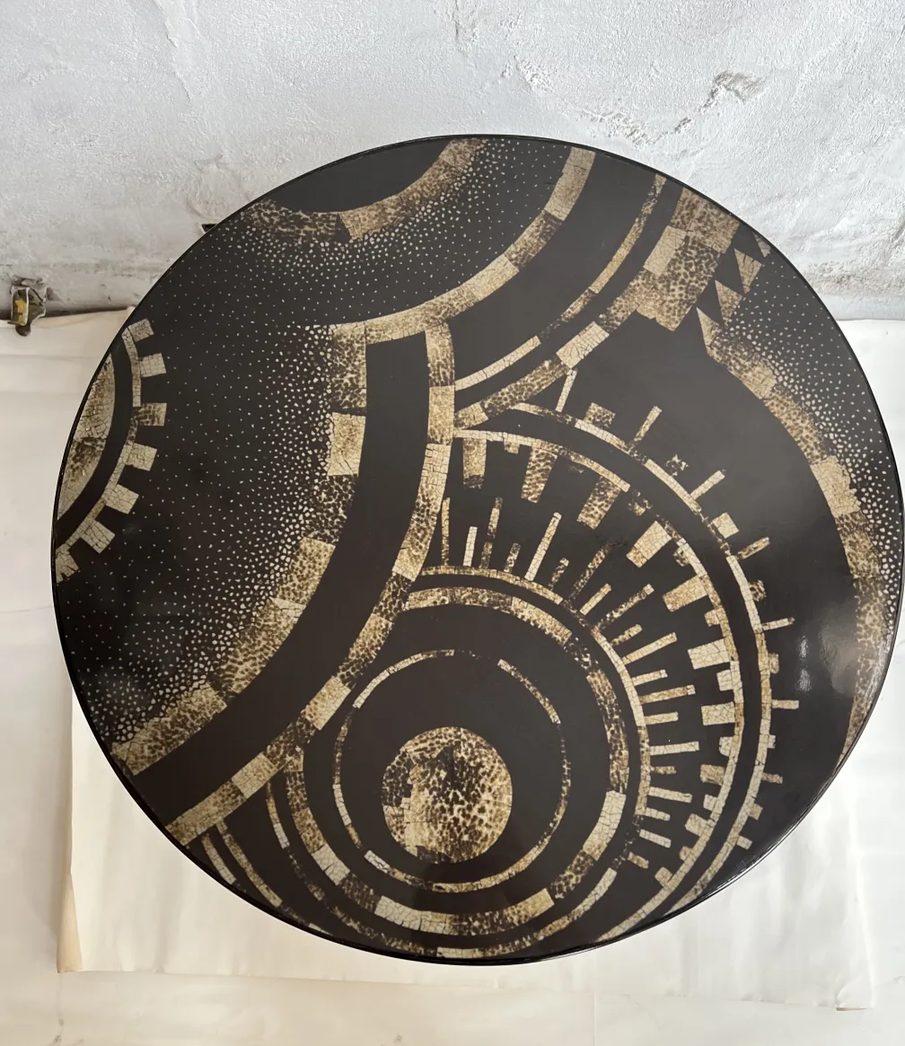 Petite table antique ronde avec design géométrique dans des tons sombres.