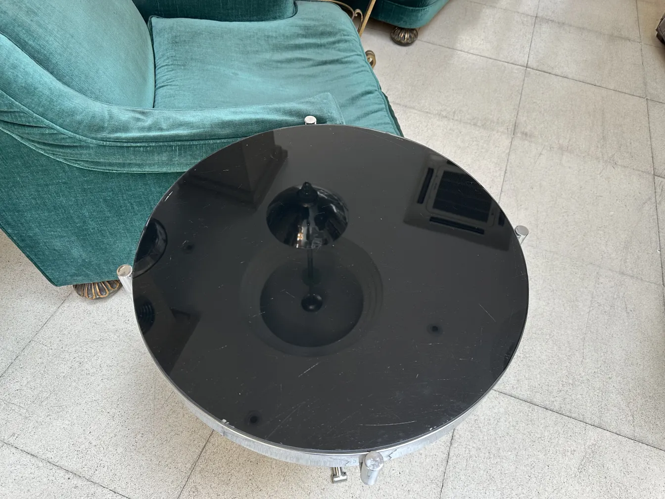 petite table ancienne ronde avec design élégant à côté d'un canapé vert