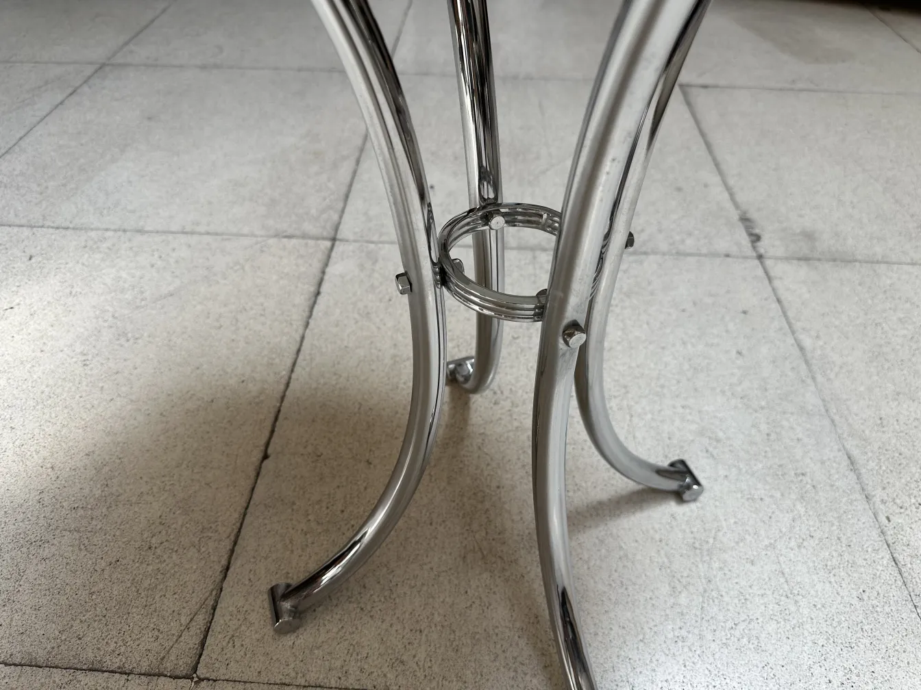 Vue des pattes courbes d'une petite table ancienne dans un cadre neutre.