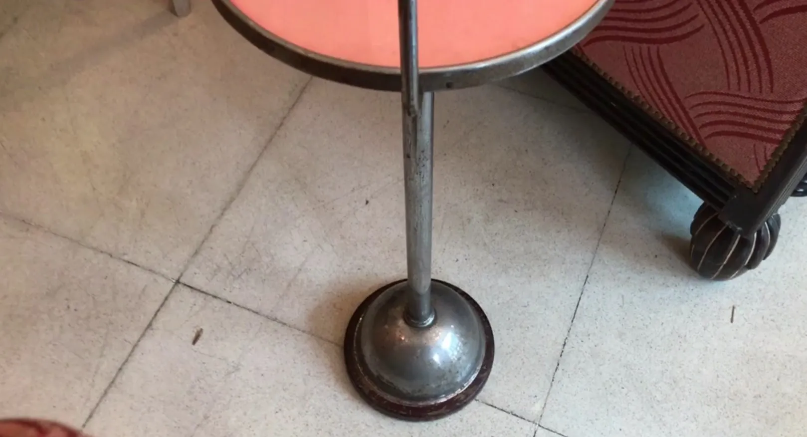 Antique small table with round base, silver color, on light floor.