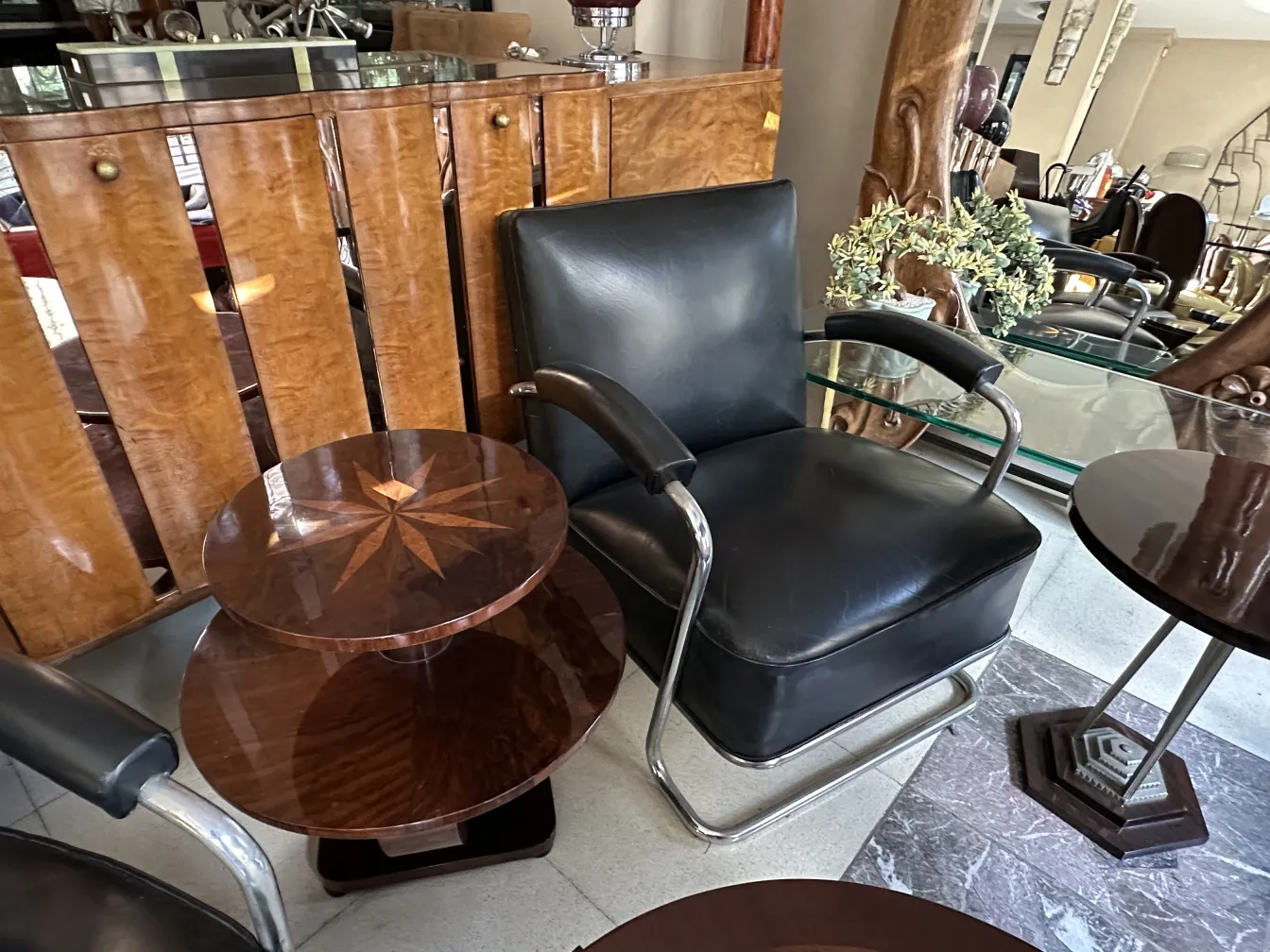 Antique small table with circular shape and star decoration, next to a chair. Cozy atmosphere with other furniture.