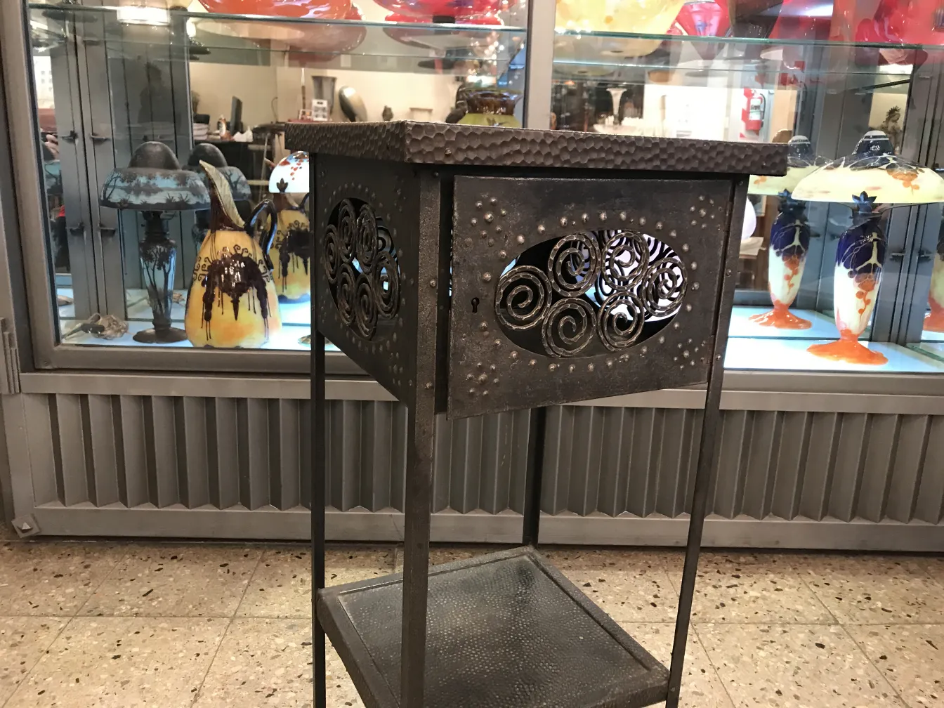 Antiker dekorativer kleiner Tisch mit geschwungenem Design, in einer klassischen Umgebung mit verschiedenen Sammlerstücken.