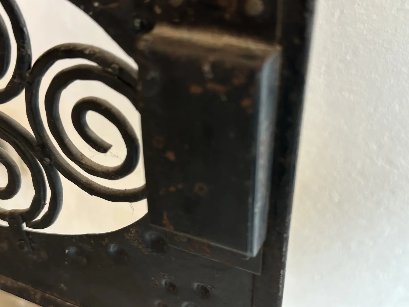 Detalle de una mesita antigua con diseño decorativo en espiral.