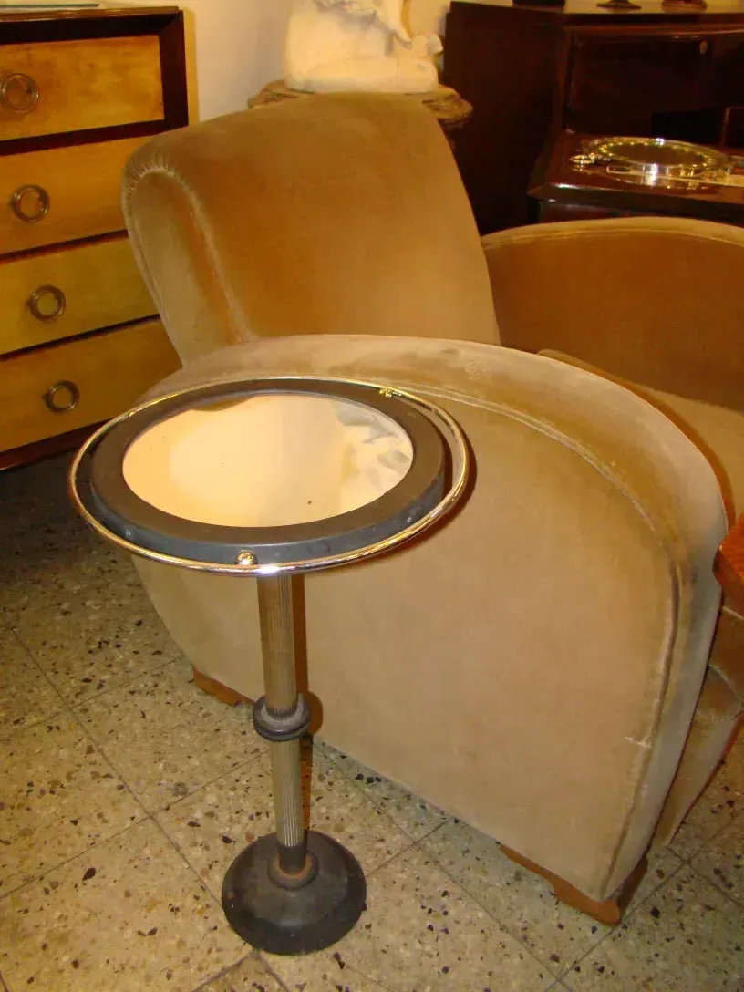 antique small table with a silver mirror, next to a soft chair in a cozy setting