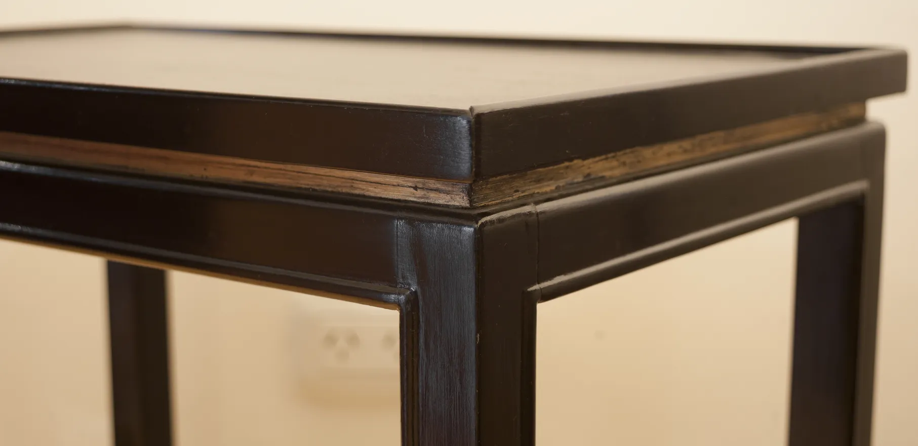 Dettaglio di un antico tavolino con finitura scura e dettagli di design.