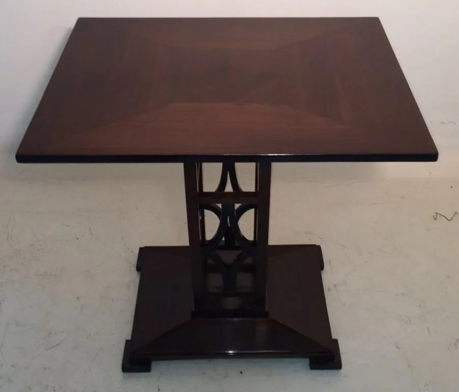 petite table ancienne avec design élégant à la base, dans un cadre neutre.