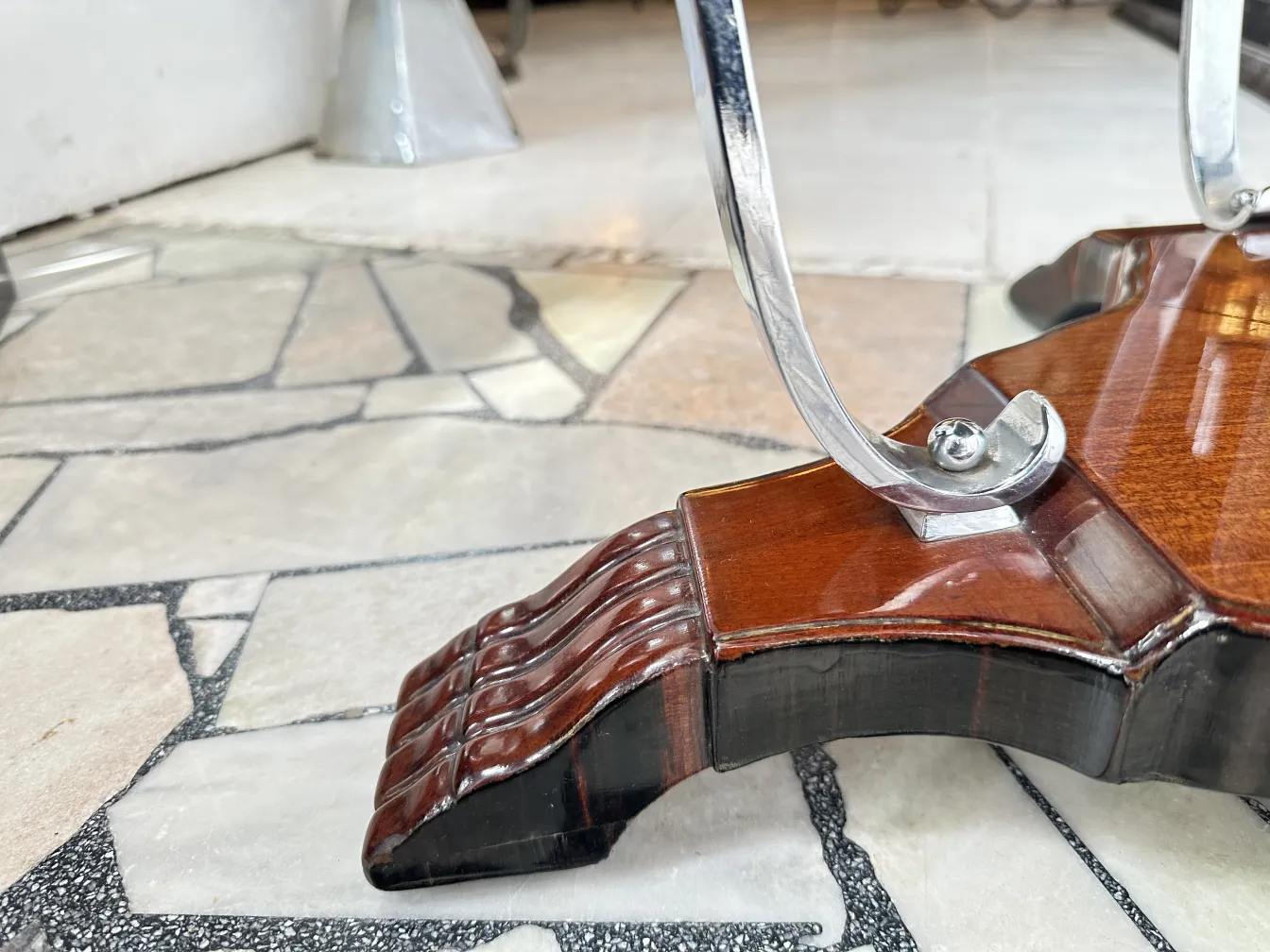 Tavolino antico con base elaborata e dettagli decorativi in un ambiente accogliente.