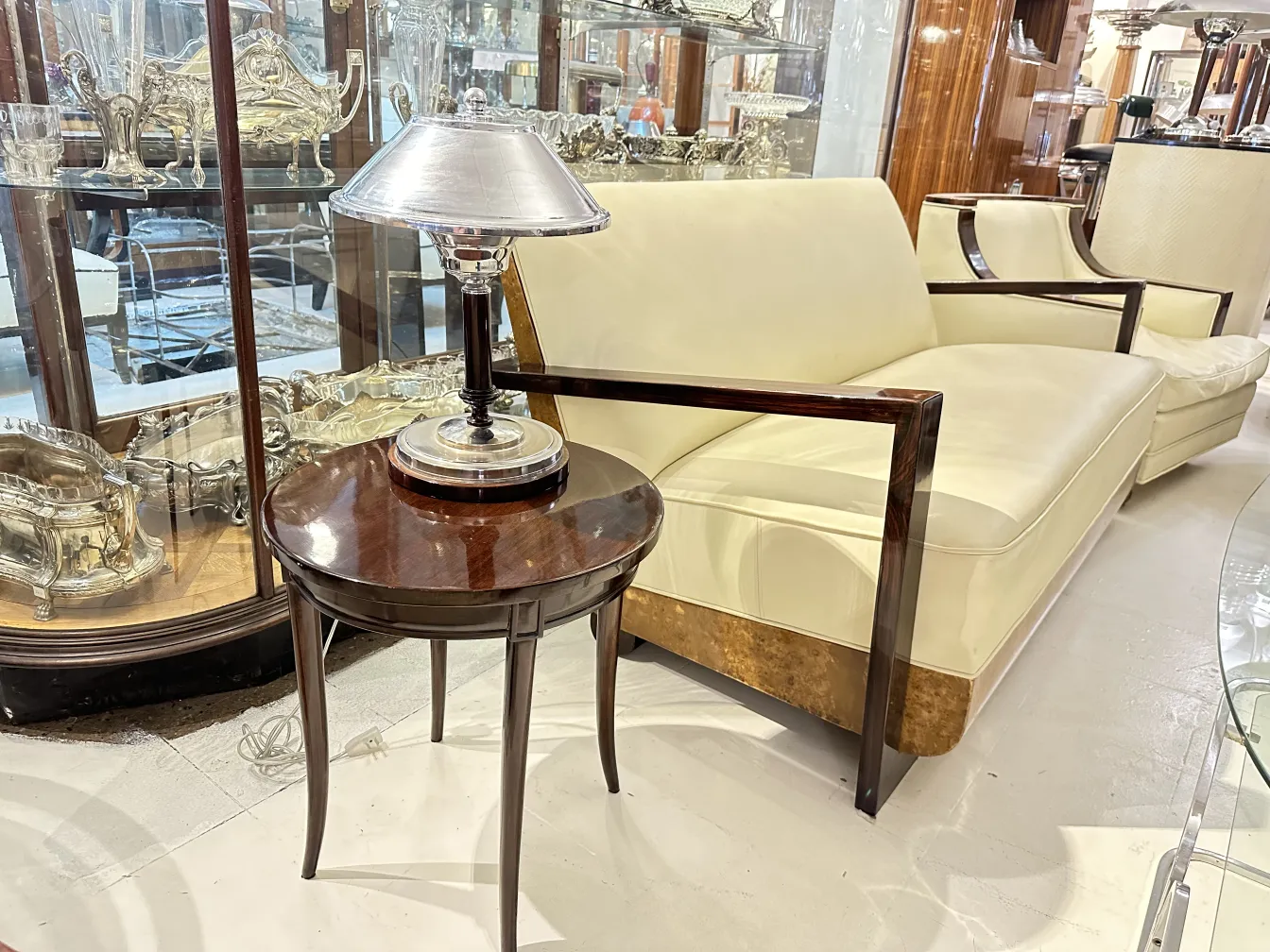 Antico tavolino rotondo con lampada sopra, divano moderno sullo sfondo