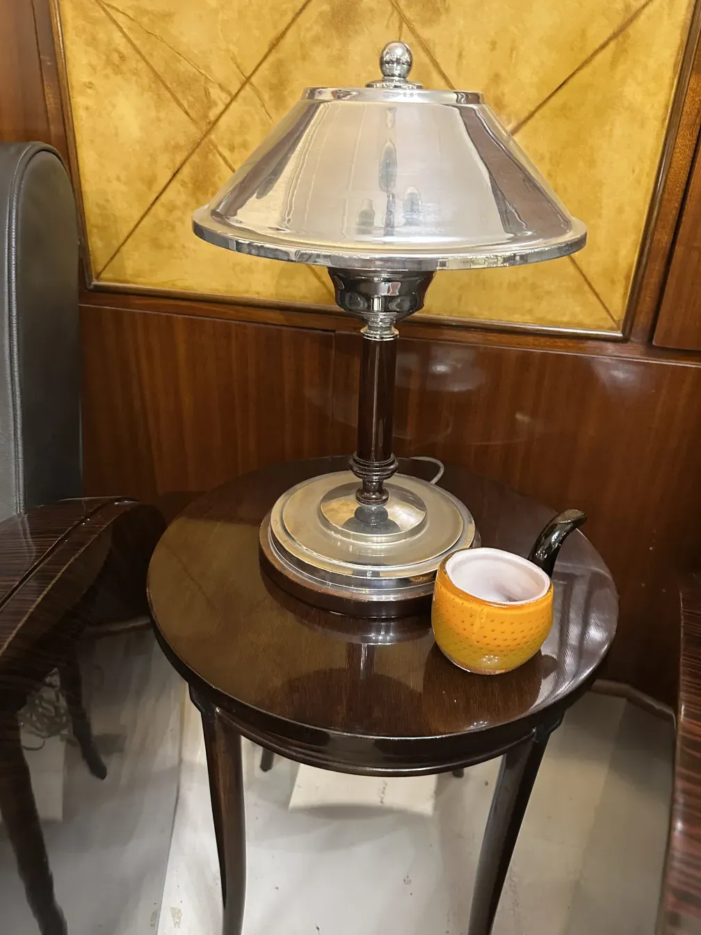 Mesinha antiga com luz e xícara amarela decorativa.