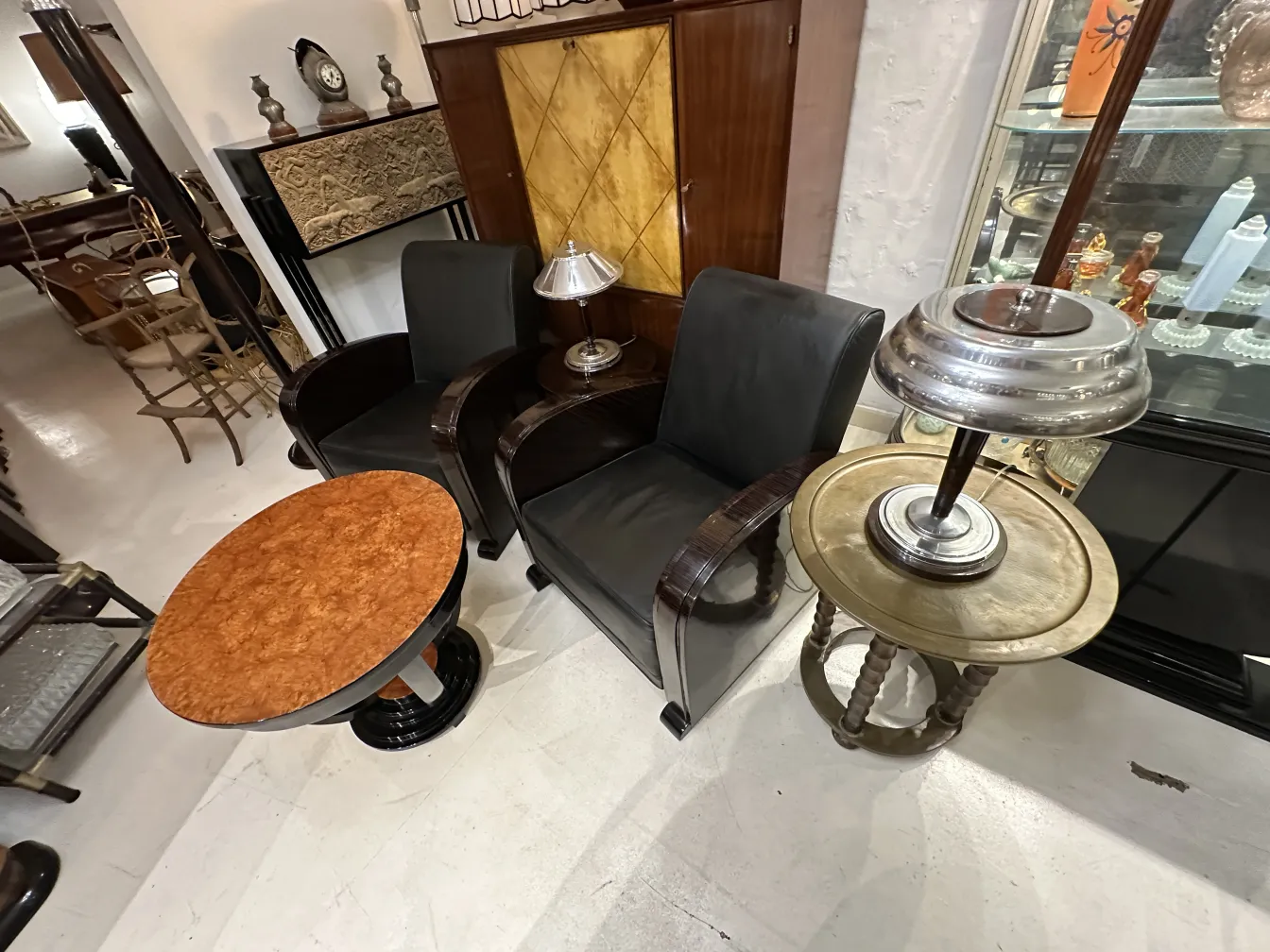 petite table ancienne de forme ovale avec surface décorative, entourée de chaises en cuir noir