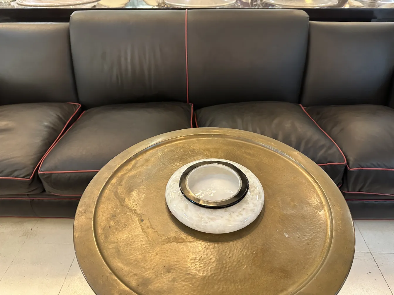 antique small table with decorative details next to a black sofa