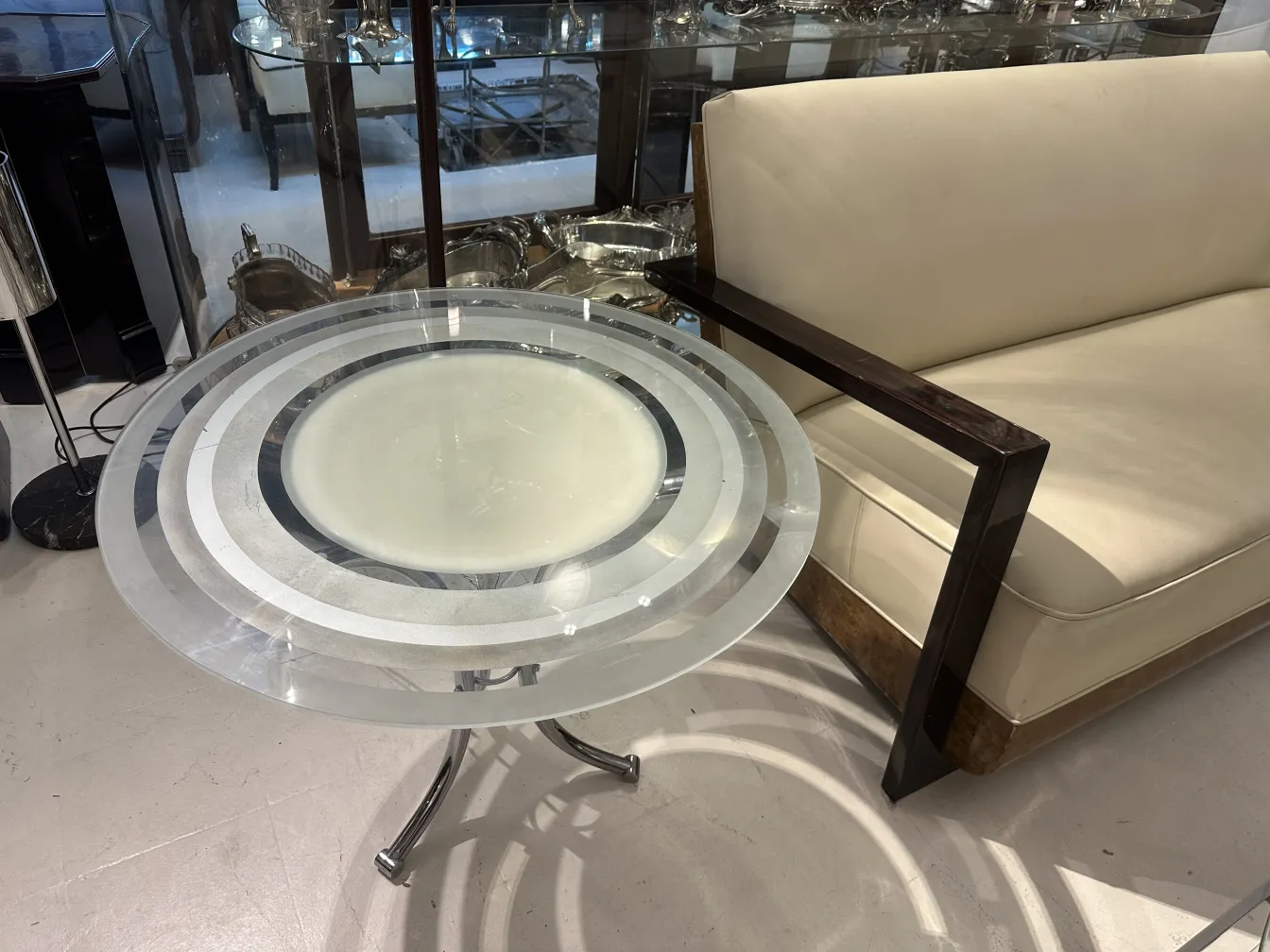 mesita antigua circular con patrones decorativos, rodeada de un sofá