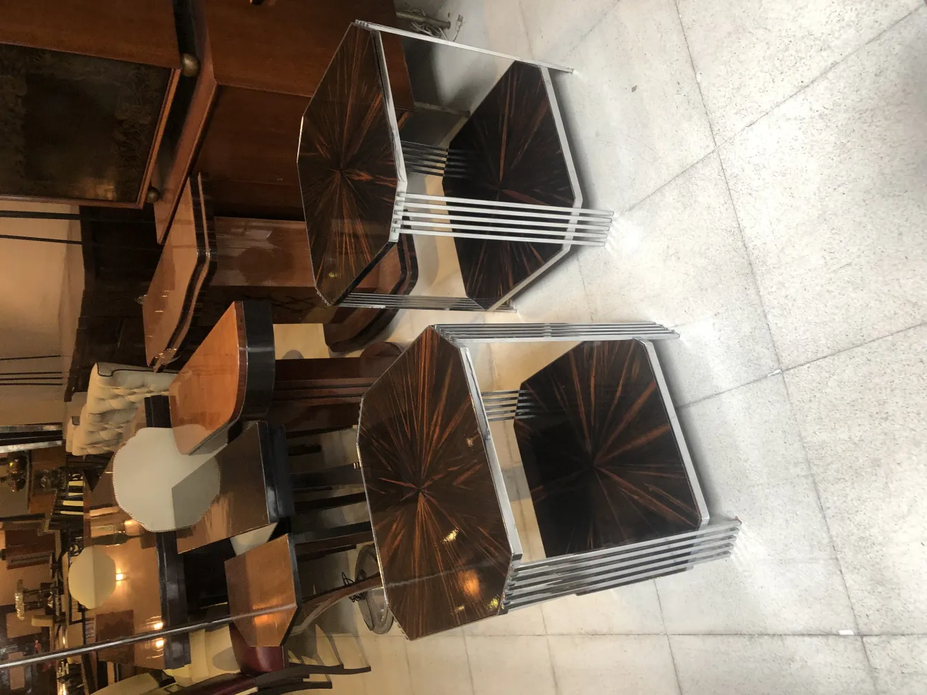 Two antique small tables set in a cozy environment with other furniture in the background.