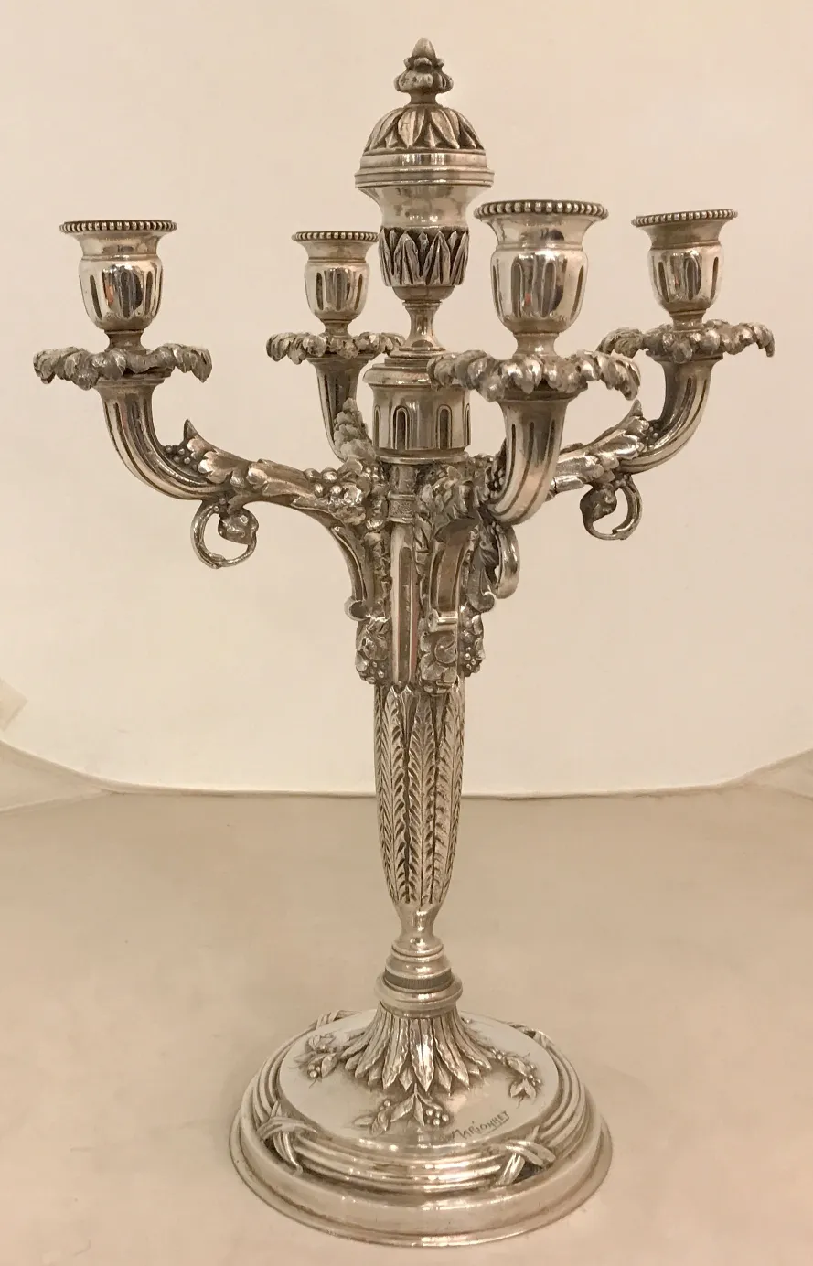 Candelabros antiguos con múltiples brazos y detalles decorativos, en un entorno neutral.