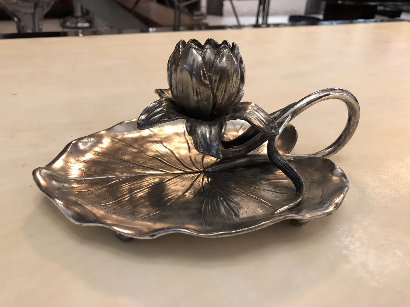 Antiker Kandelaber mit floralem Design auf einer blattförmigen Basis.