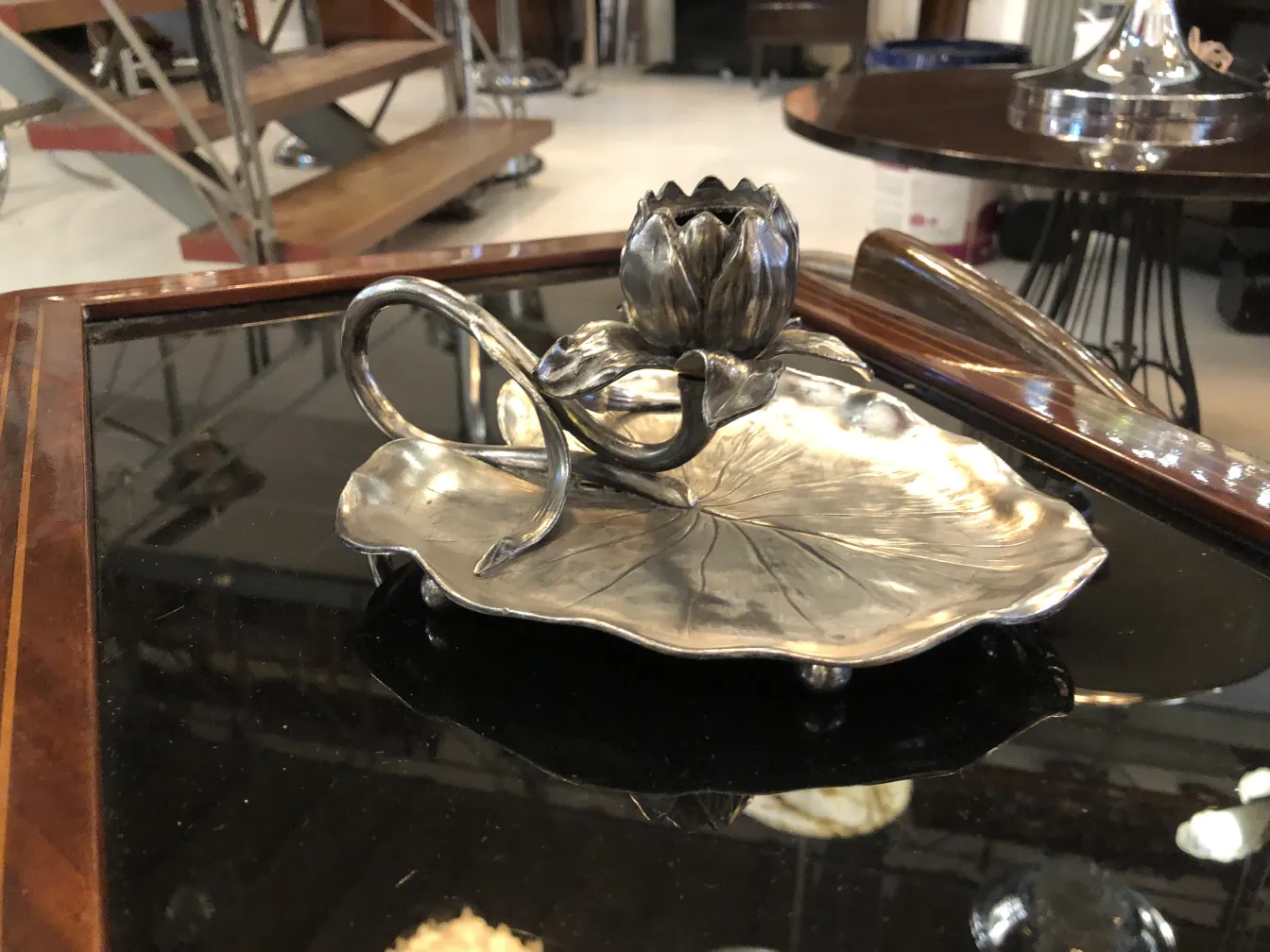 candelabro antigo com design de flor de lótus e base decorativa em um ambiente de antiguidades