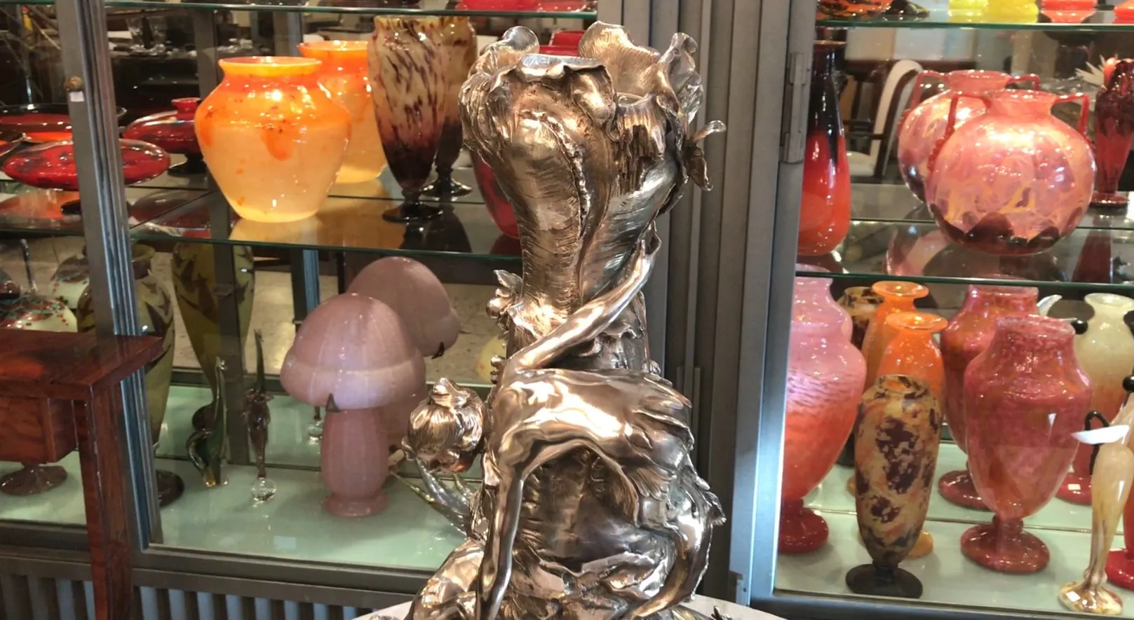 Dois vasos antigos em estilo art nouveau, com formas elegantes e detalhes decorativos, expostos em um ambiente de antiguidades.